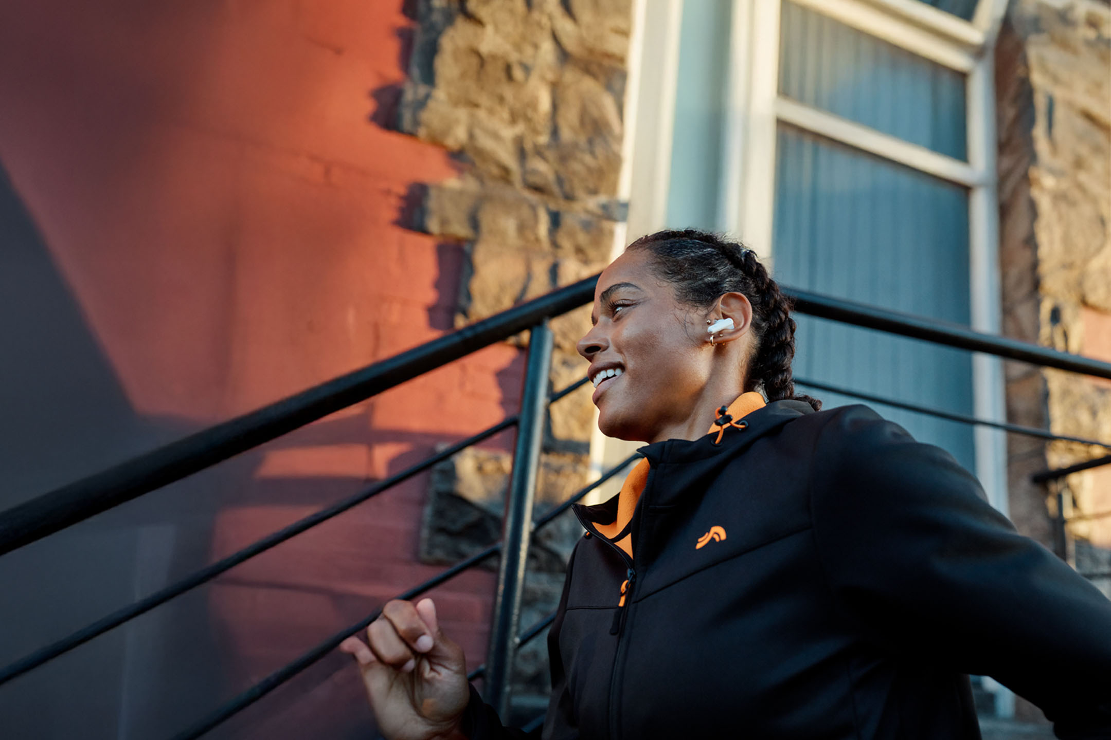 Woman jogging with earphones, wearing a jacket.