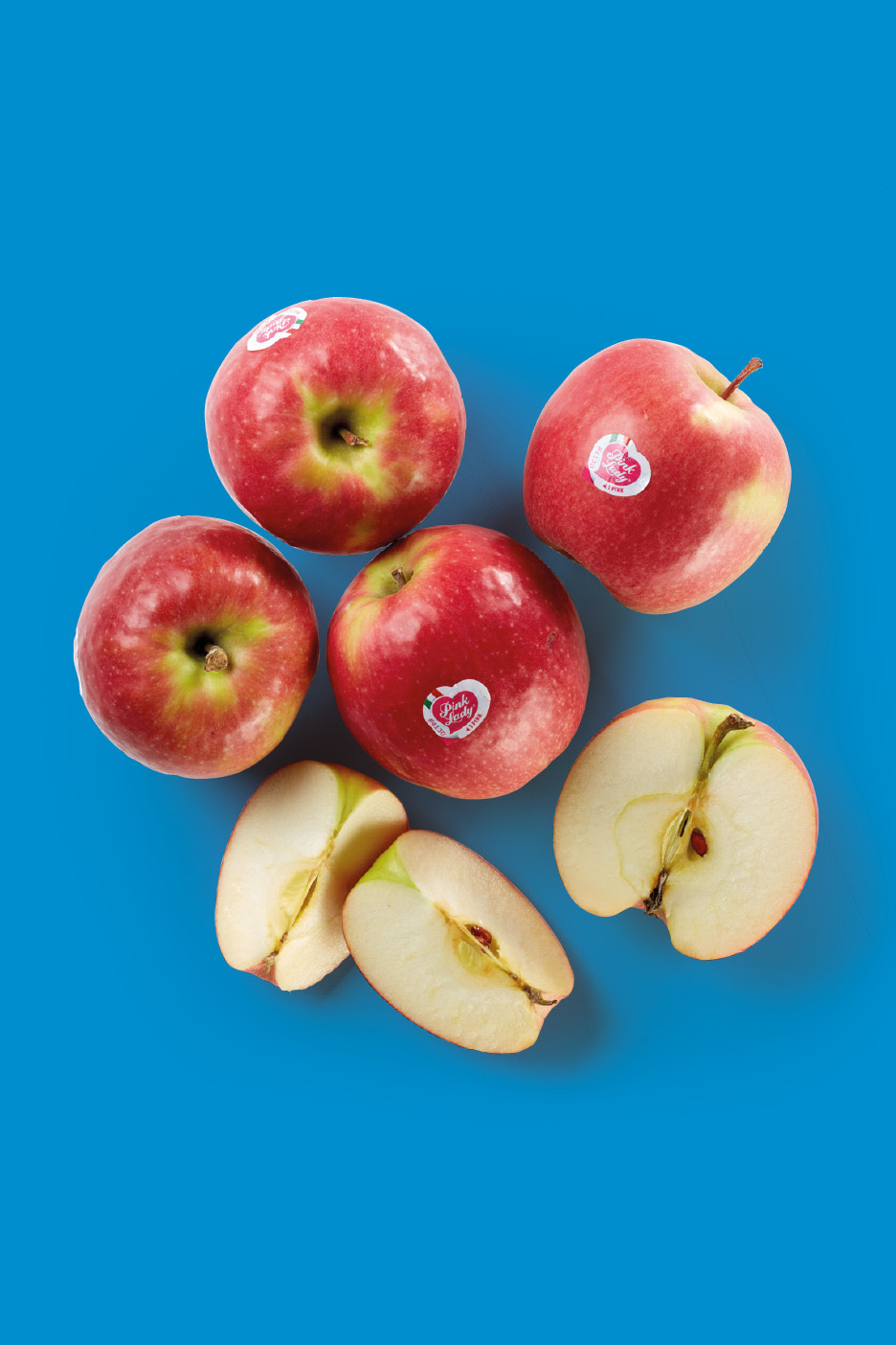 Red apples, some whole and some sliced, on a blue background.