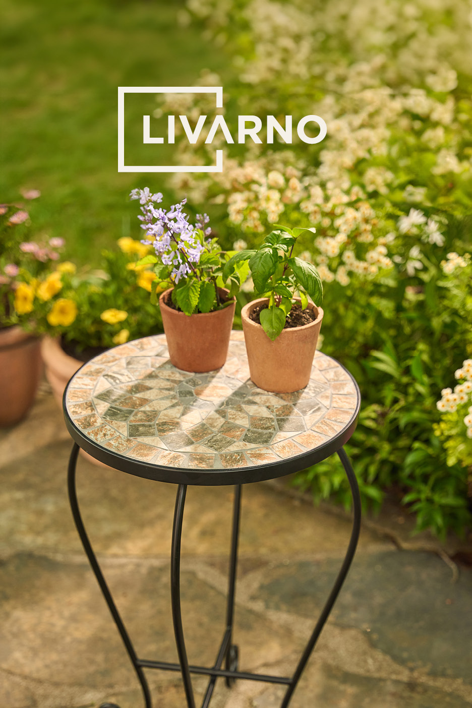 Two potted plants on a mosaic garden side table in a sunny garden.