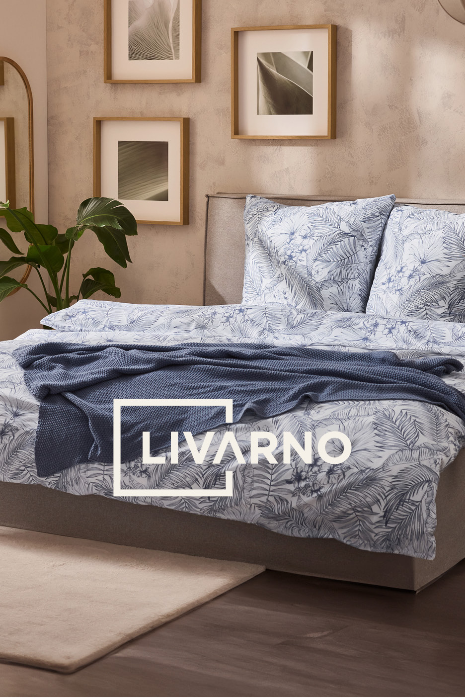 Bedroom with a bed featuring blue and white tropical leaf bedding, a blue knitted throw, and framed botanical prints.