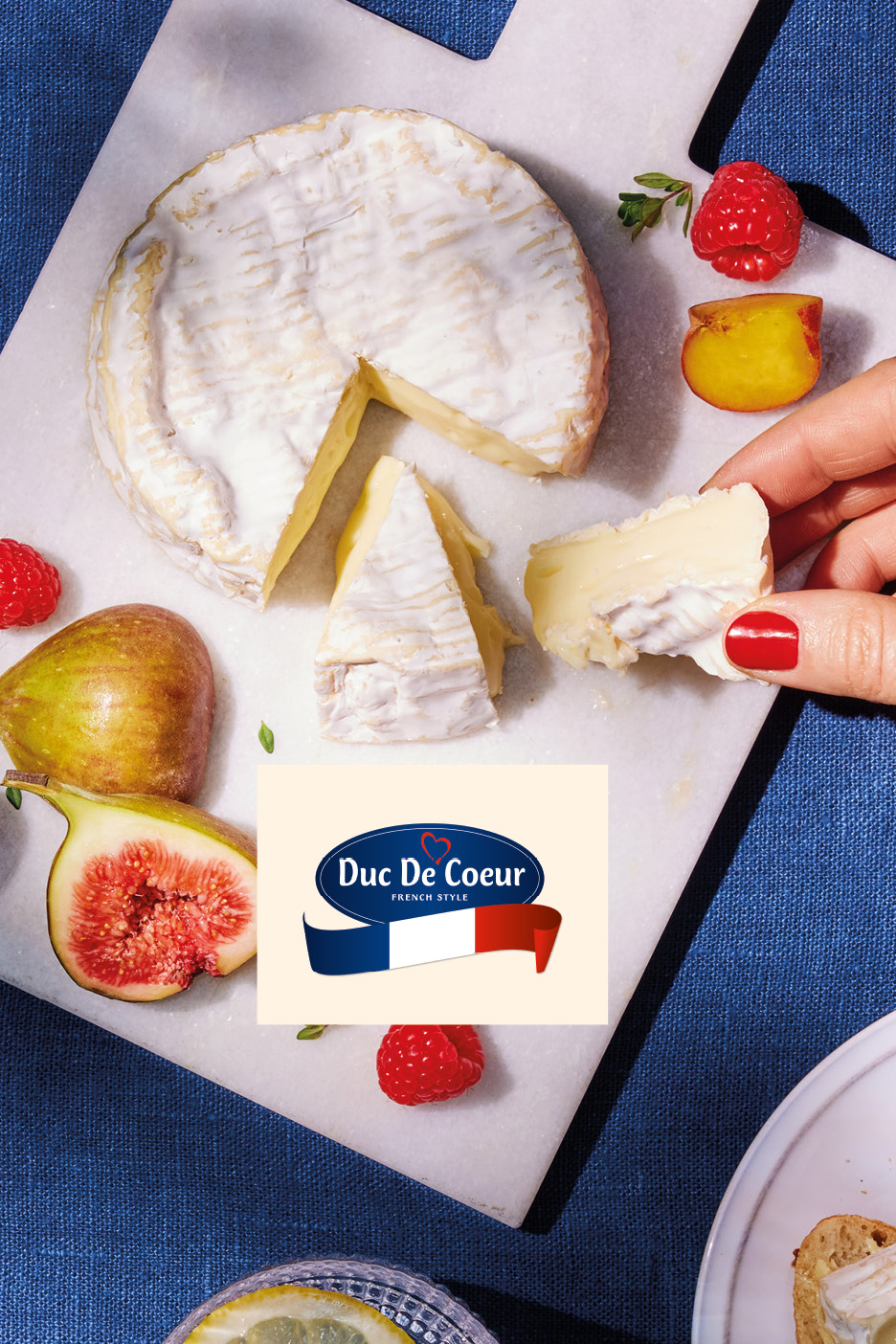 Creamy French-style cheese with figs, raspberries, and peaches on a marble board.